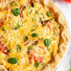 Tomato pie with layers of tomatoes, basil and cheesy mayo topping in a glass pie dish.
