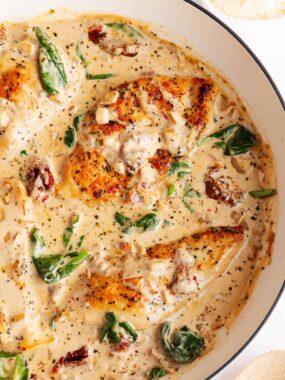 Close-up of creamy Tuscan chicken with browned chicken breasts, wilted spinach, and sun-dried tomatoes.