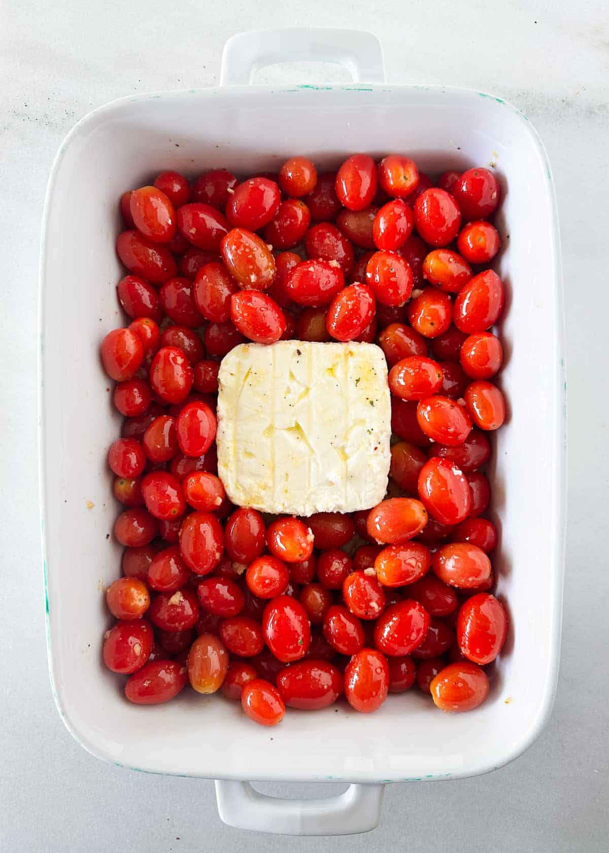 Baked feta pasta ingredients in white dish.