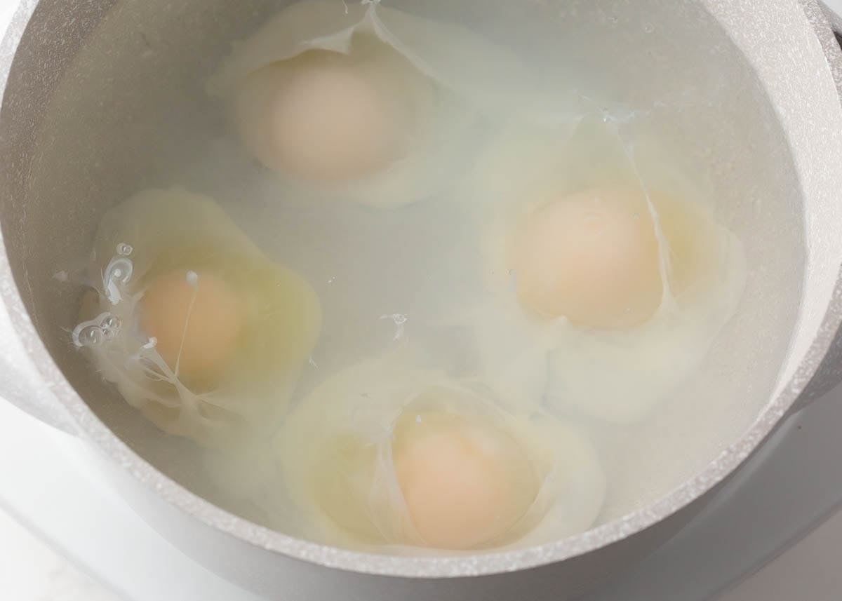 Poaching eggs in simmering water for classic eggs benedict.
