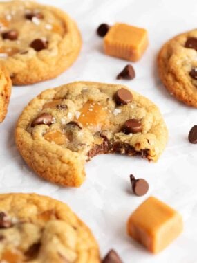salted caramel chocolate chip cookies with one cookie on the counter with a bite missing.