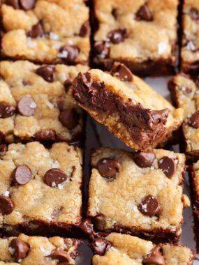 Soft and chewy chocolate chip cookie bars cut into squares with one titled to chow gooey melted chocolate.