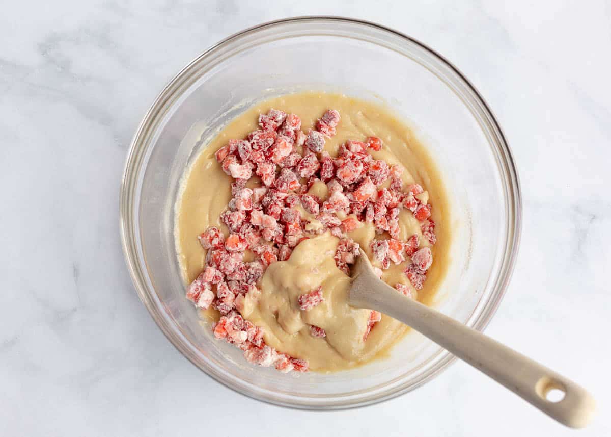 Folding flour-coated diced strawberries into strawberry quick bread batter.