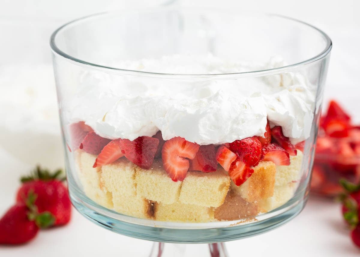 First layer of pound cake cubes and chopped strawberries added to a glass trifle dish.