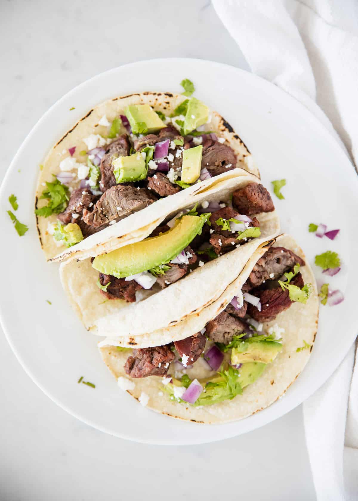 Steak tacos on white plate.