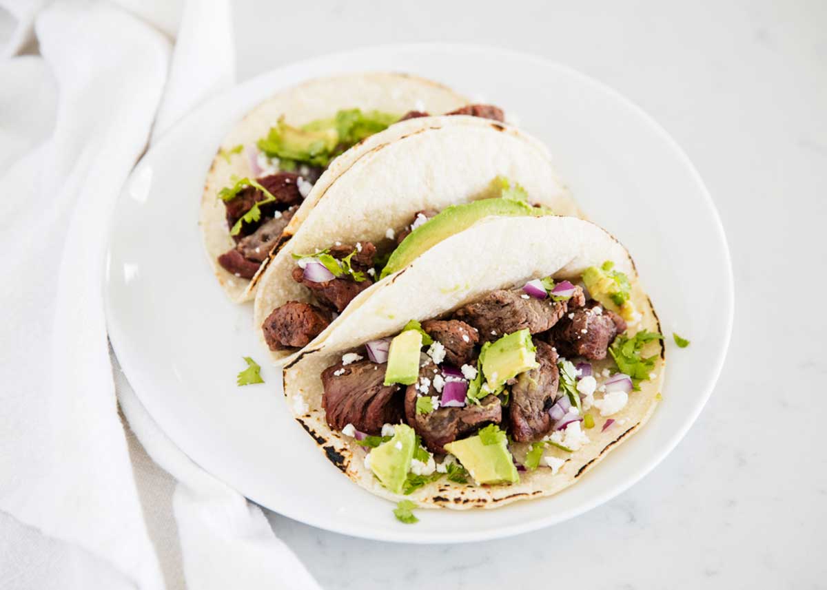 Steak tacos on white plate.