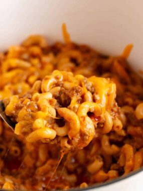 Cheeseburger casserole recipe in a white pot with serving spoon.
