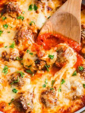 Chicken parmesan meatballs in pan with serving spoon.