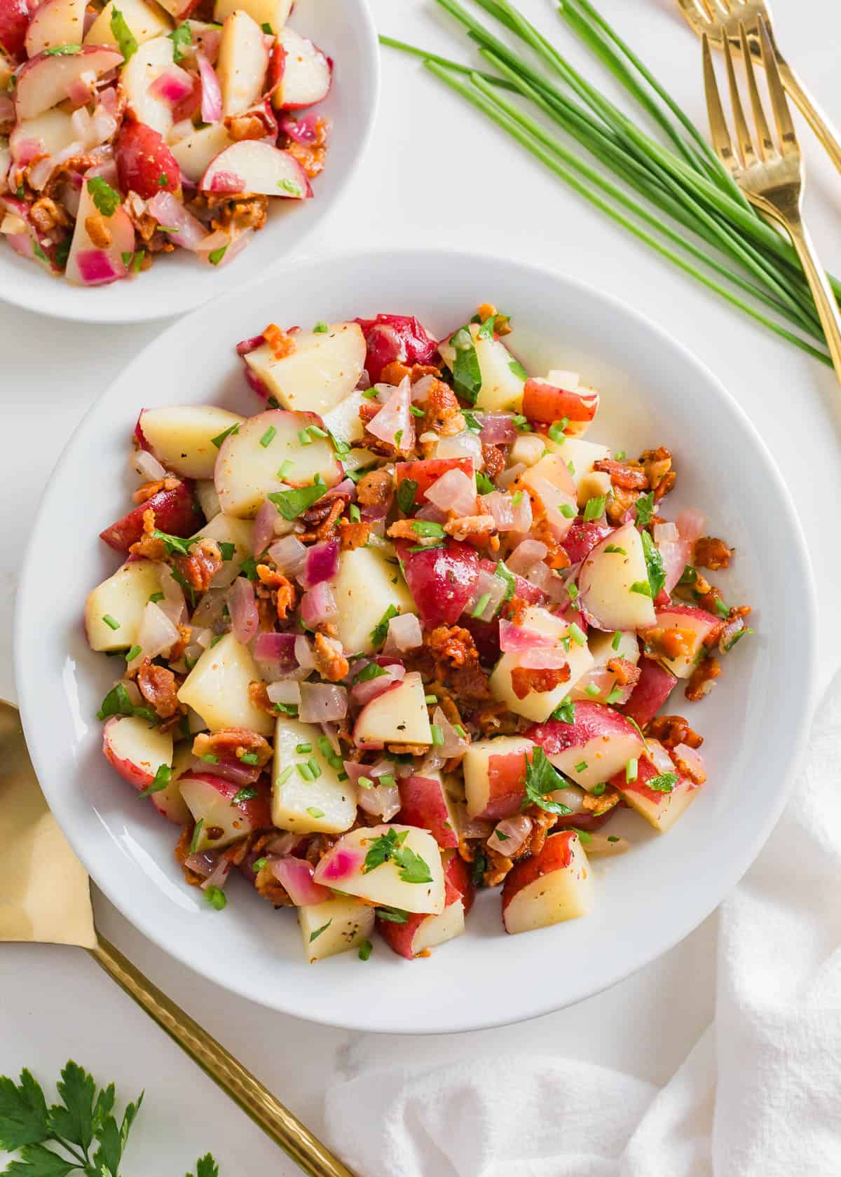 Hot German potato salad with bacon in a bowl, garnished with chives.
