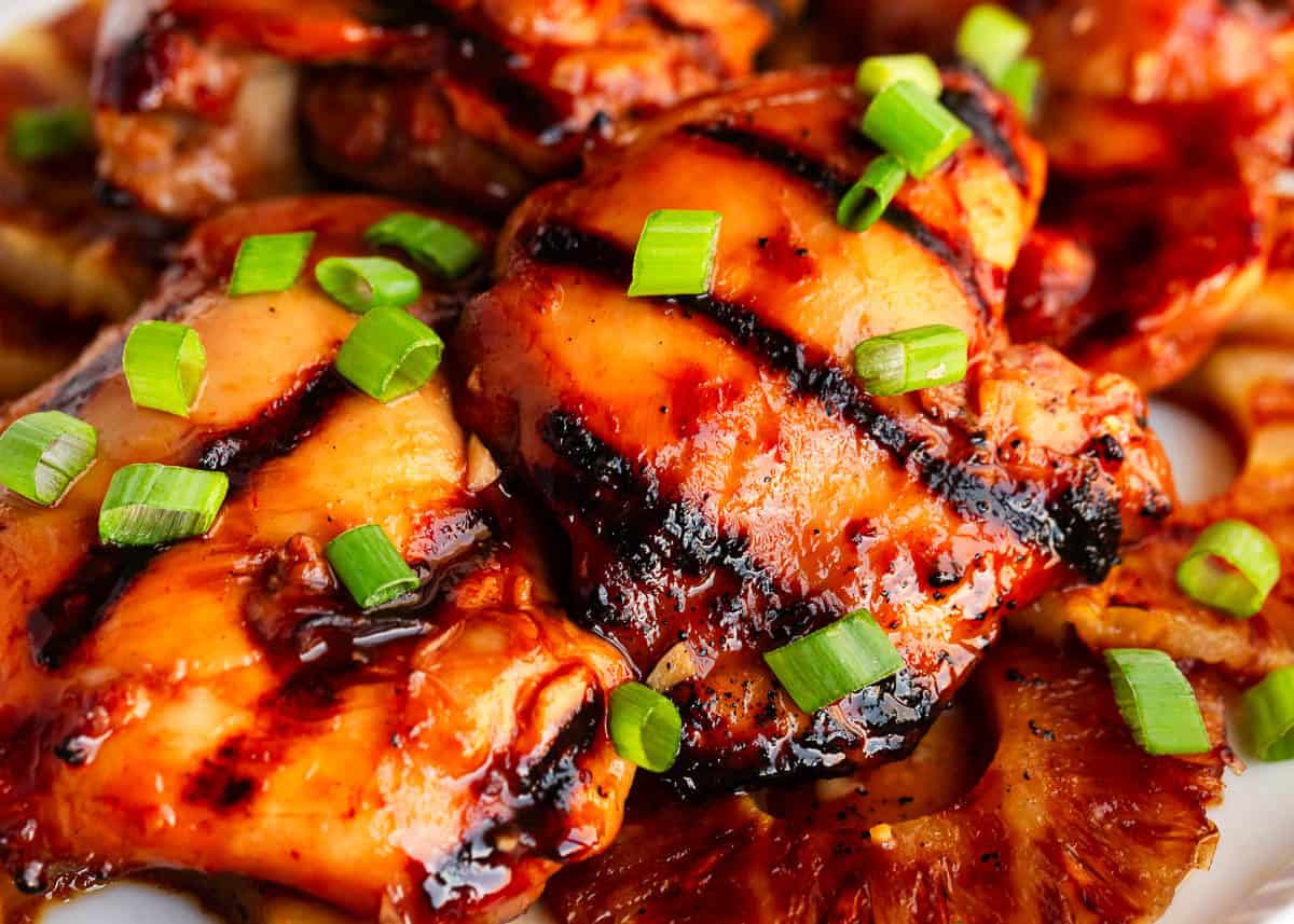 Close up of grilled Hawaiian huli huli chicken with garnish.