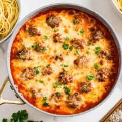 Chicken parmesan meatballs simmered in marinara and covered with cheese in a skillet.