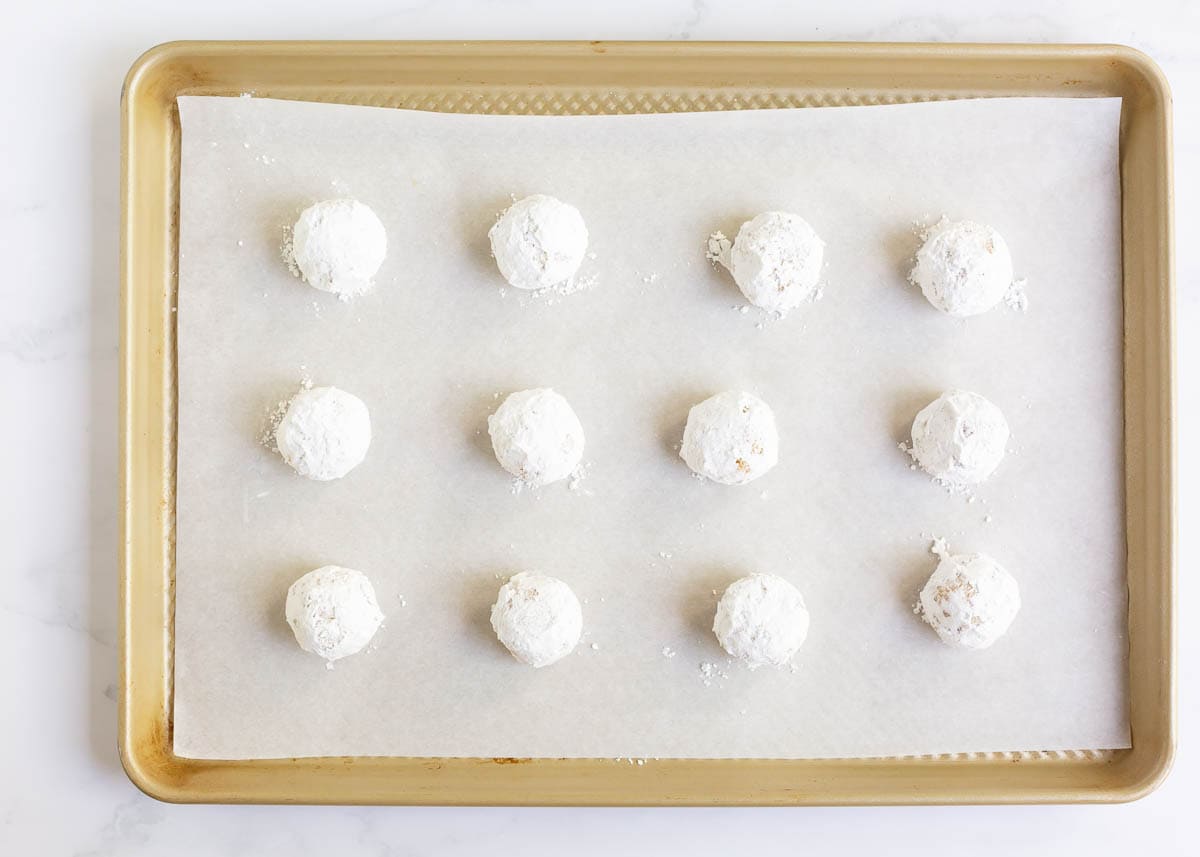 Lemon crinkle cookies covered in powdered sugar on baking sheet.