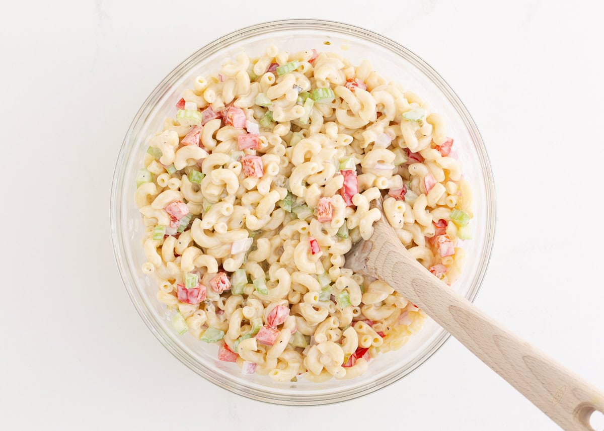 Stirring dressing into macaroni salad.