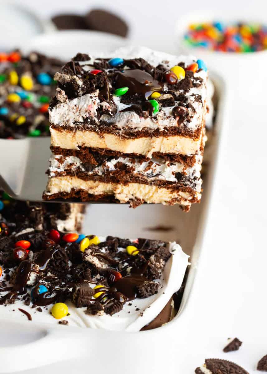 This ice cream sandwich cake is the best summer dessert! It's easy to make this no-bake treat with ice cream sandwiches, hot fudge sauce, Oreo's and Cool Whip. A slice of ice cream sandwich cake being served from the pan.