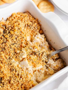 Poppy seed chicken casserole with serving spoon in white dish.