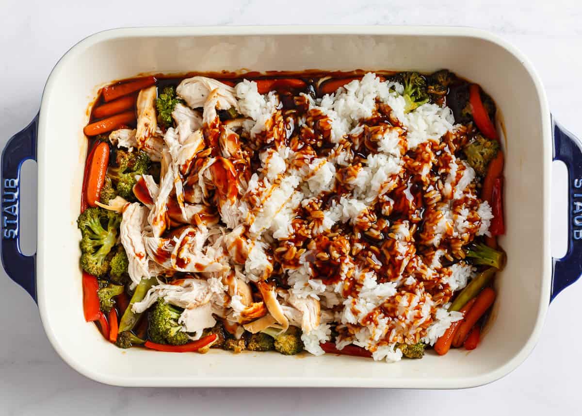 All you need for this easy chicken teriyaki casserole is chicken, cooked rice, veggies, and teriyaki sauce for a quick, healthy, and flavorful meal any night of the week! Shredded chicken with vegetables and teriyaki sauce in a white baking dish.