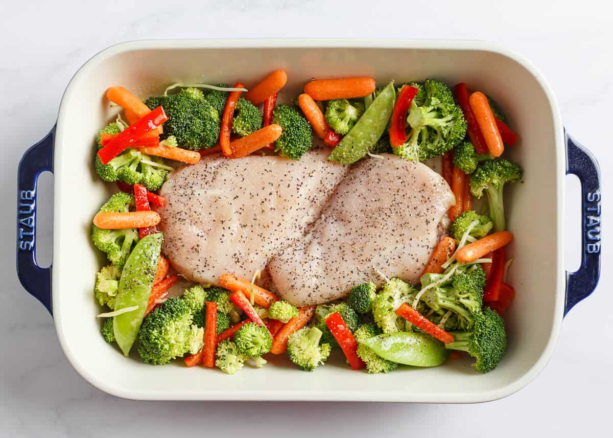 All you need for this easy chicken teriyaki casserole is chicken, cooked rice, veggies, and teriyaki sauce for a quick, healthy, and flavorful meal any night of the week! Unbaked chicken and vegetables in a white baking dish.