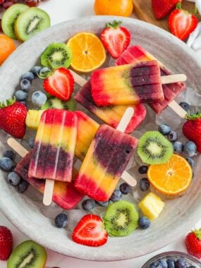 A tray with rainbow popsicles and fresh fruit.
