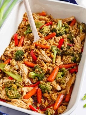 Teriyaki chicken casserole in a white baking dish with serving spoon.