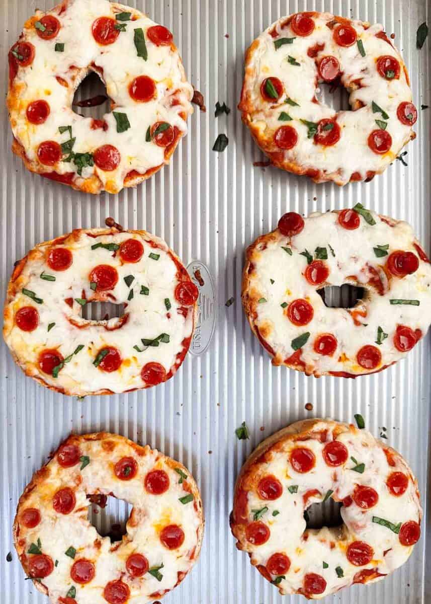 Pizza bagels on a baking sheet.