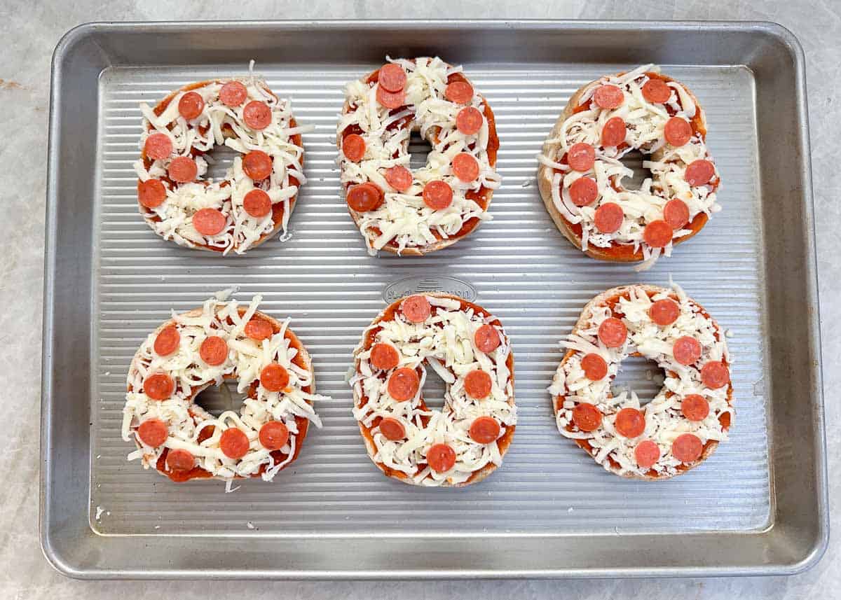 Pizza bagels on a baking sheet.