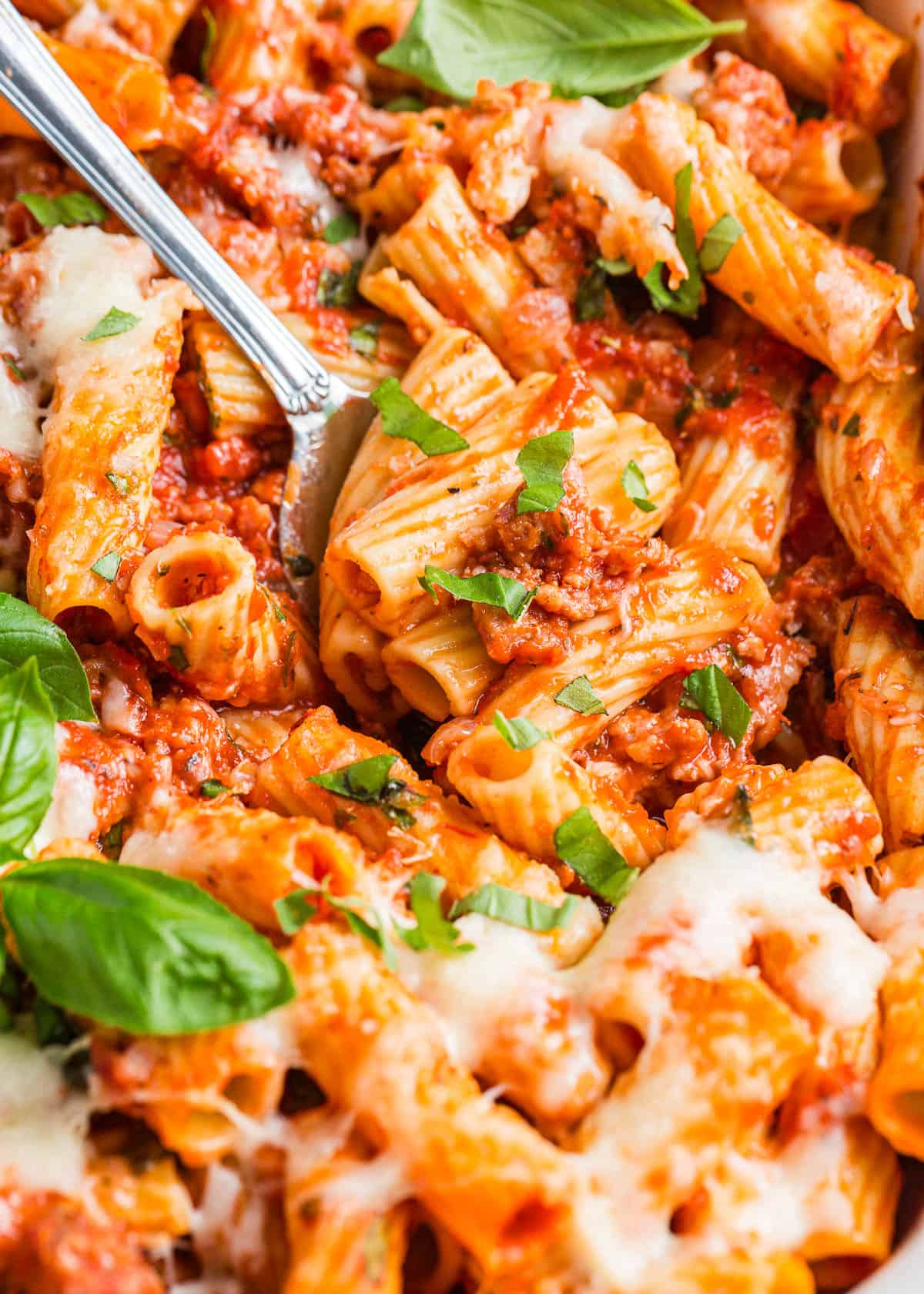 Turn a classic rigatoni dish into baked rigatoni by adding layers of mozzarella cheese to rigatoni pasta and meat sauce, then bake it until bubbly for an easy weeknight dinner. Baked rigatoni with basil.