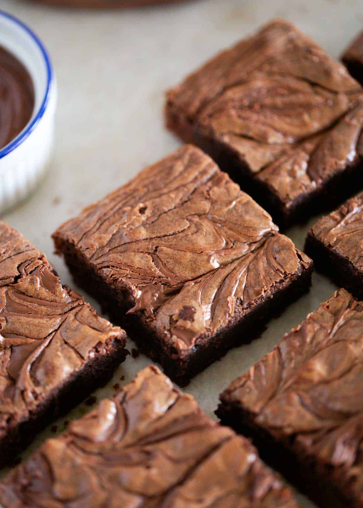 These Nutella brownies are rich, fudgy and full of chocolate hazelnut flavor. These chewy brownies are so irresistible and easy to make homemade with only 3 ingredients! Nutella brownies cut into squares with a swirled chocolate hazelnut topping.