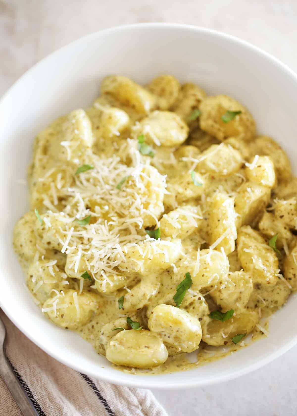 This 15-minute pesto gnocchi is easy to make with only 4 ingredients! Crispy, pillowy gnocchi is tossed with a creamy pesto sauce that will be a new favorite weeknight dinner. Pesto gnocchi in a bowl.
