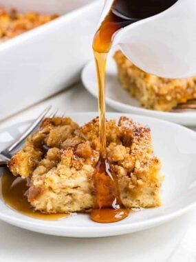 A slice of baked French toast casserole with syrup being poured it.