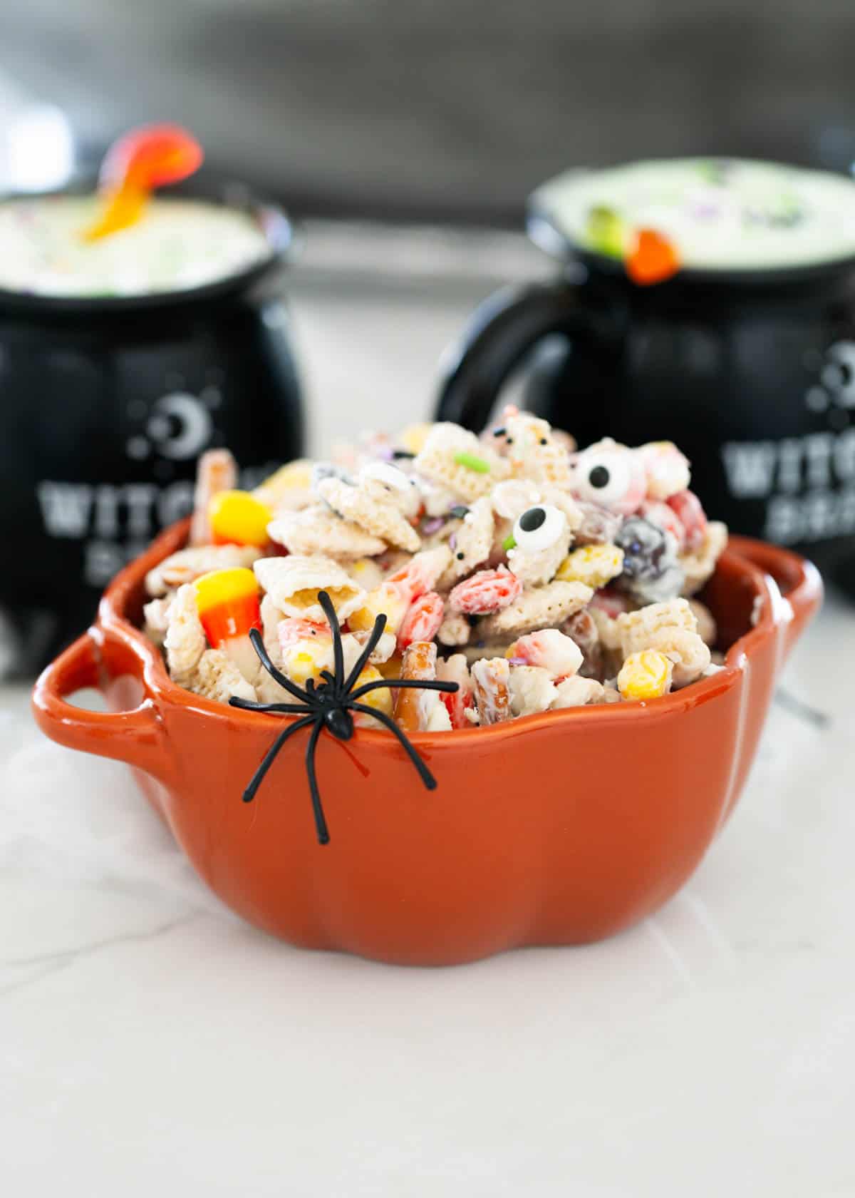 This Halloween Chex mix is sweet, crunchy and feeds a crowd! Everyone always loves this addicting monster munch with cereal, pretzels and candy coated in white chocolate. Halloween chex mix in a bowl.