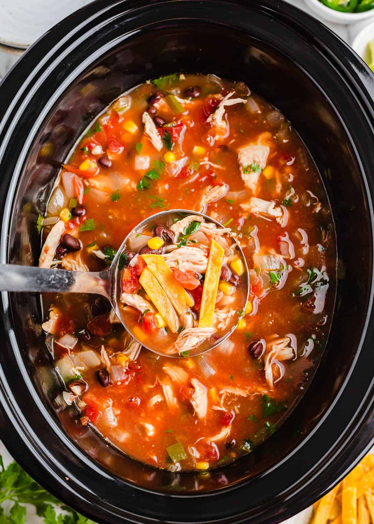 Layers of Mexican-inspired flavors simmer for hours in this crock pot chicken tortilla soup that is made with chicken, beans, corn, and plenty of herbs and spices! Crockpot Chicken Tortilla Soup in a slow cooker.