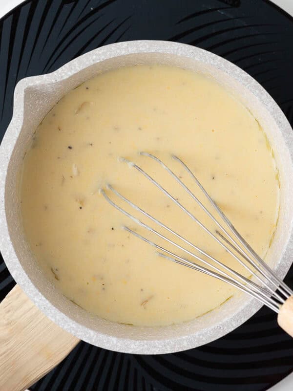 Making a sauce for cheesy scalloped potatoes in a saucepan.