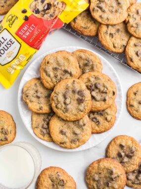 Toll House chocolate chip cookies on a plate next to a baking sheet.