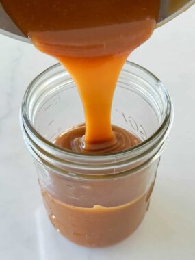 Pouring easy caramel sauce into jar.