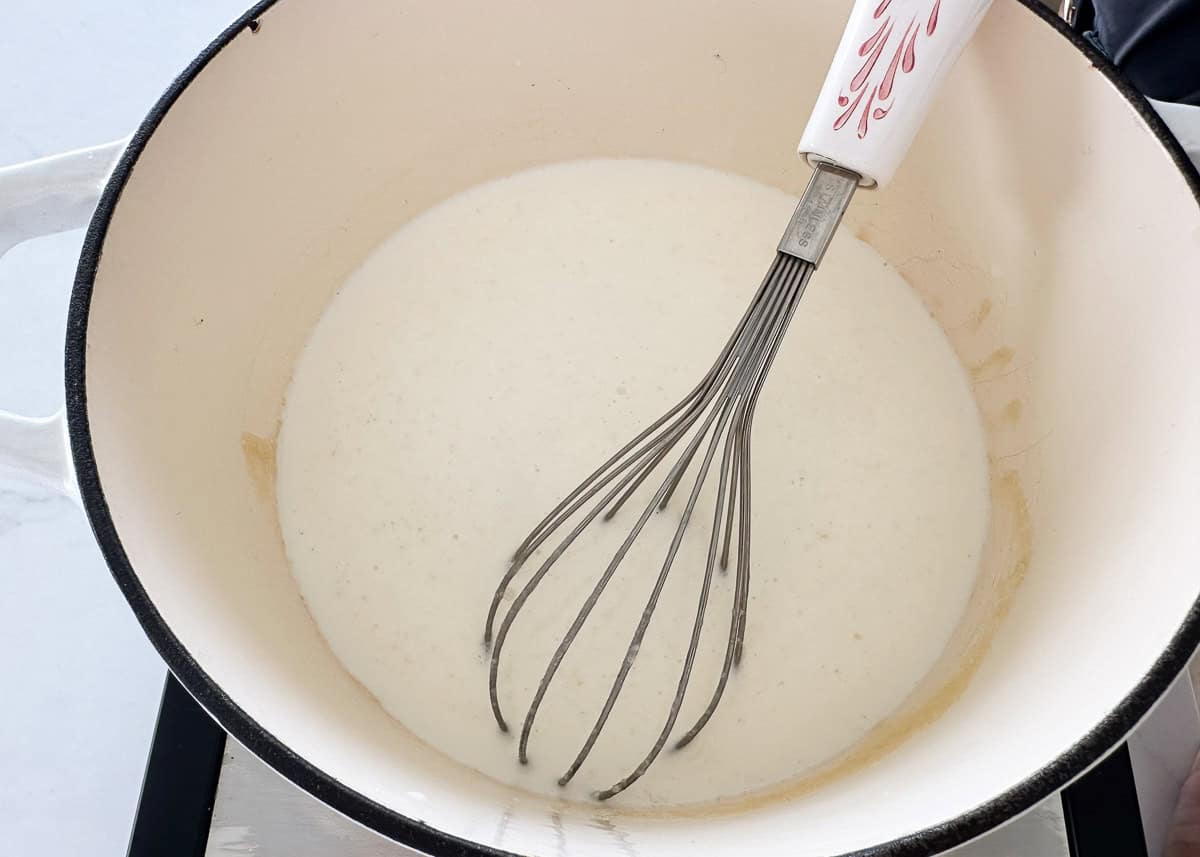 Whisking in milk to a pot.