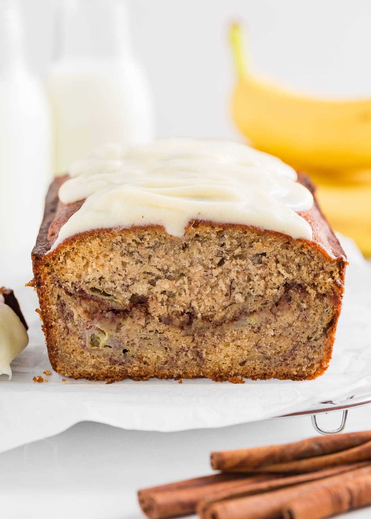 This cinnamon roll banana bread is part banana bread and part cinnamon roll with cinnamon sugar swirled throughout the middle and topped with a cream cheese glaze! Cinnamon roll banana bread with cream cheese frosting.