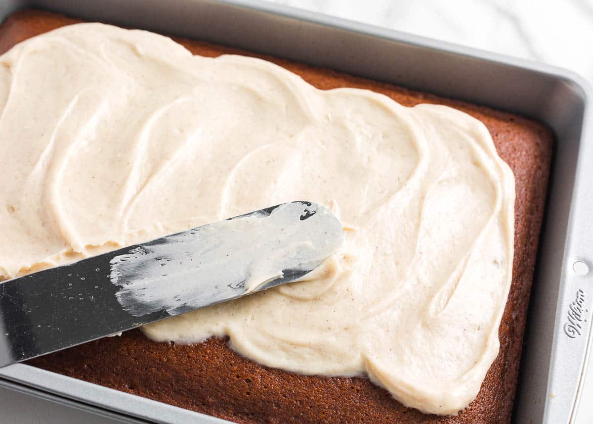 Spreading frosting on top of gingerbread cake.