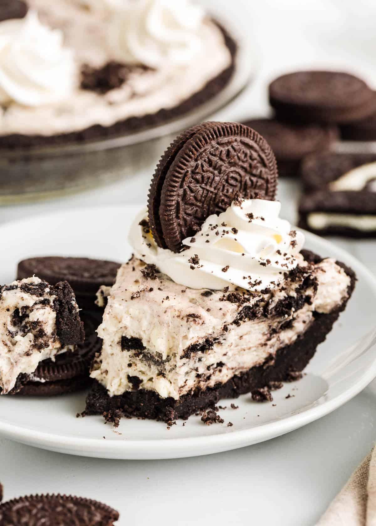 Made with a chocolaty Oreo cookie crust and a creamy Oreo cheesecake filling using simple ingredients, this easy no-bake Oreo pie sets up in the fridge in just a few hours! Slice of oreo pie on a plate.