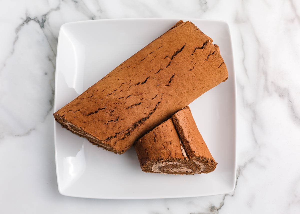This Christmas make a traditional yule log cake (bûche de noël). A chocolate sponge cake is filled with creamy mascarpone, then covered with chocolate ganache for the bark. Showing how to shape yule log cake.