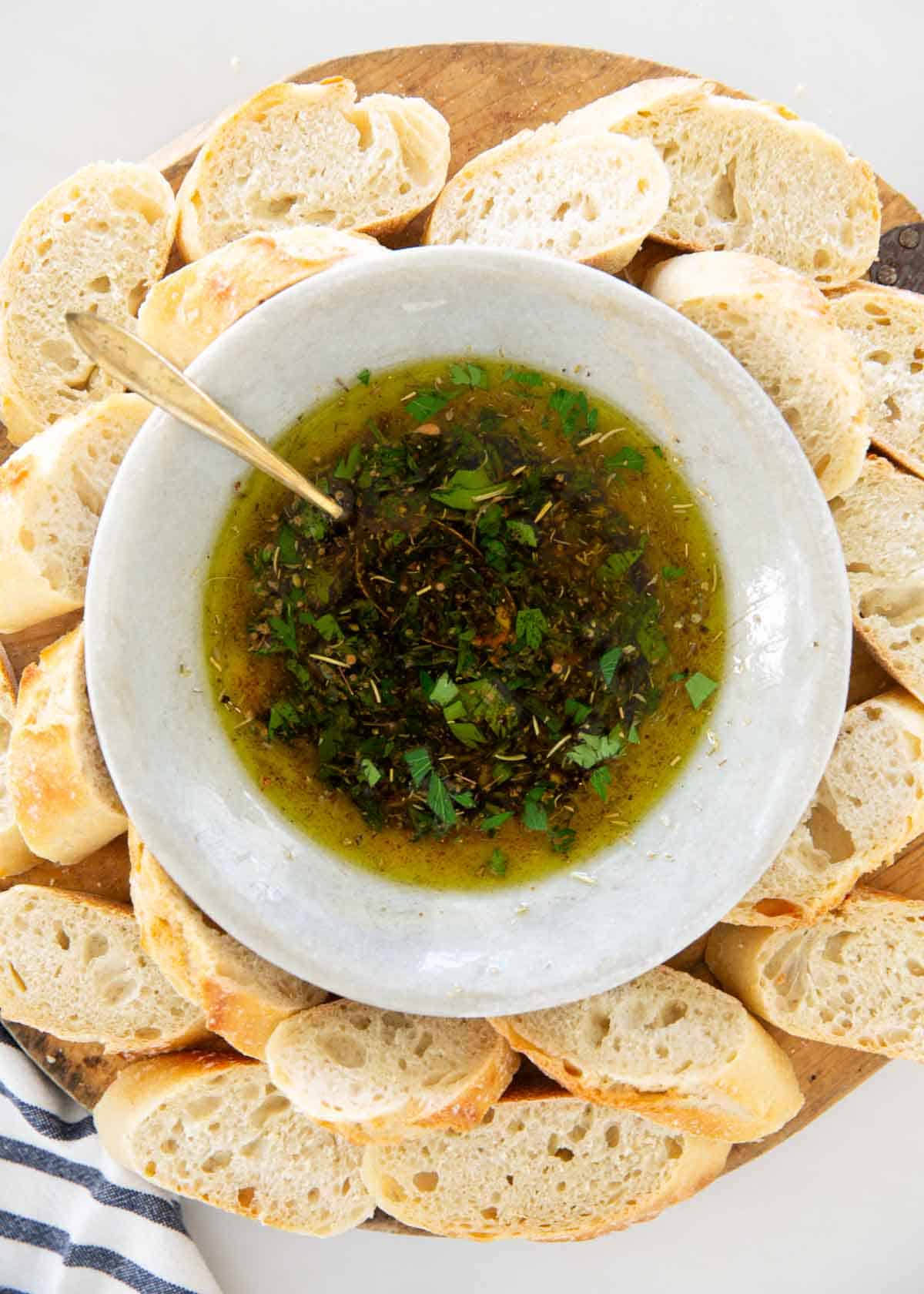 Restaurant-style bread dipping oil is made with a blend of dried spices, fresh herbs and olive oil. It's easy to make and never fails to impress when served with crusty bread. Bread dipping oil with sliced french baguette.