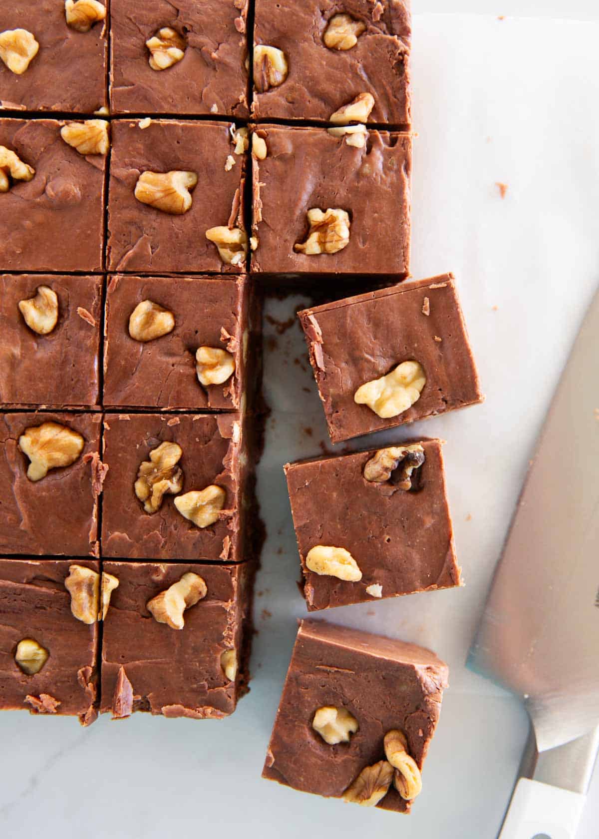 Just like the original recipe from the back of the Kraft marshmallow creme jar, fantasy fudge is a classic holiday treat for Christmas made with chocolate chips and walnuts! Fantasy fudge cut into squares.