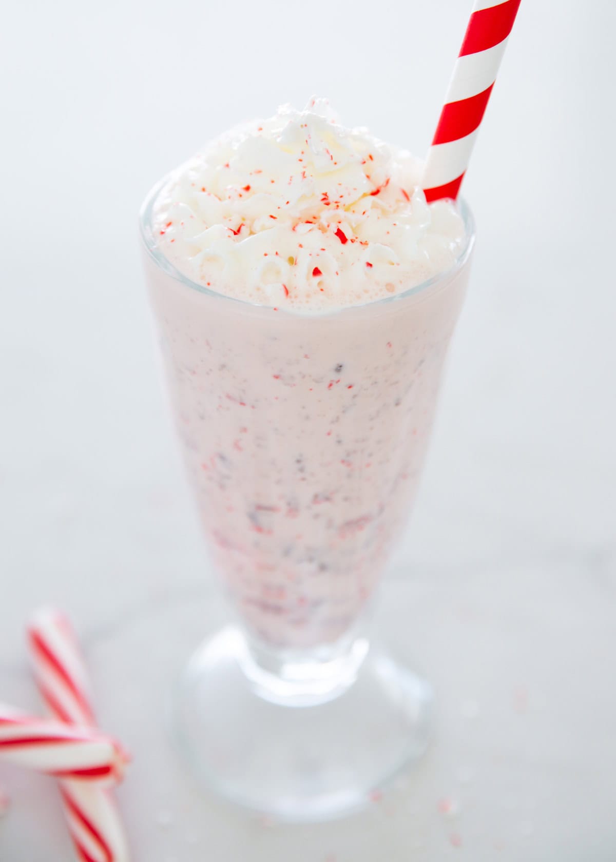 This tastes just like the Chick-Fil-A peppermint milkshake! This copycat recipe is easy to make at home and is thick and creamy with peppermint flavor and chocolate chips. Peppermint milkshake in a glass cup.