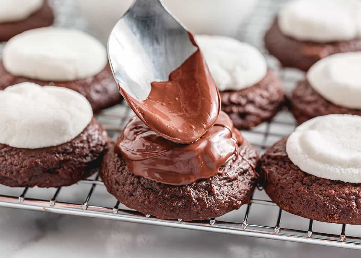 Drizzling chocolate over chocolate marshmallow cookie.