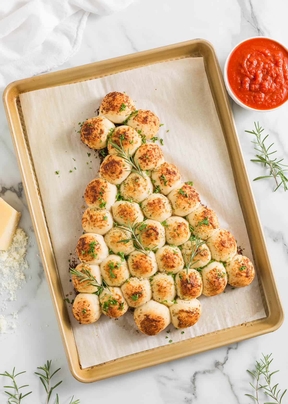 This Christmas tree pull apart bread is a must-make holiday appetizer with fluffy balls of dough stuffed with melty mozzarella baked in the shape of a Christmas tree! Christmas tree pull apart bread on a pan.