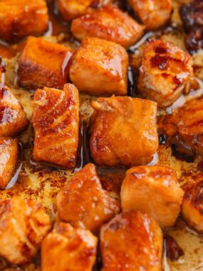 Salmon bites cooking in pan.