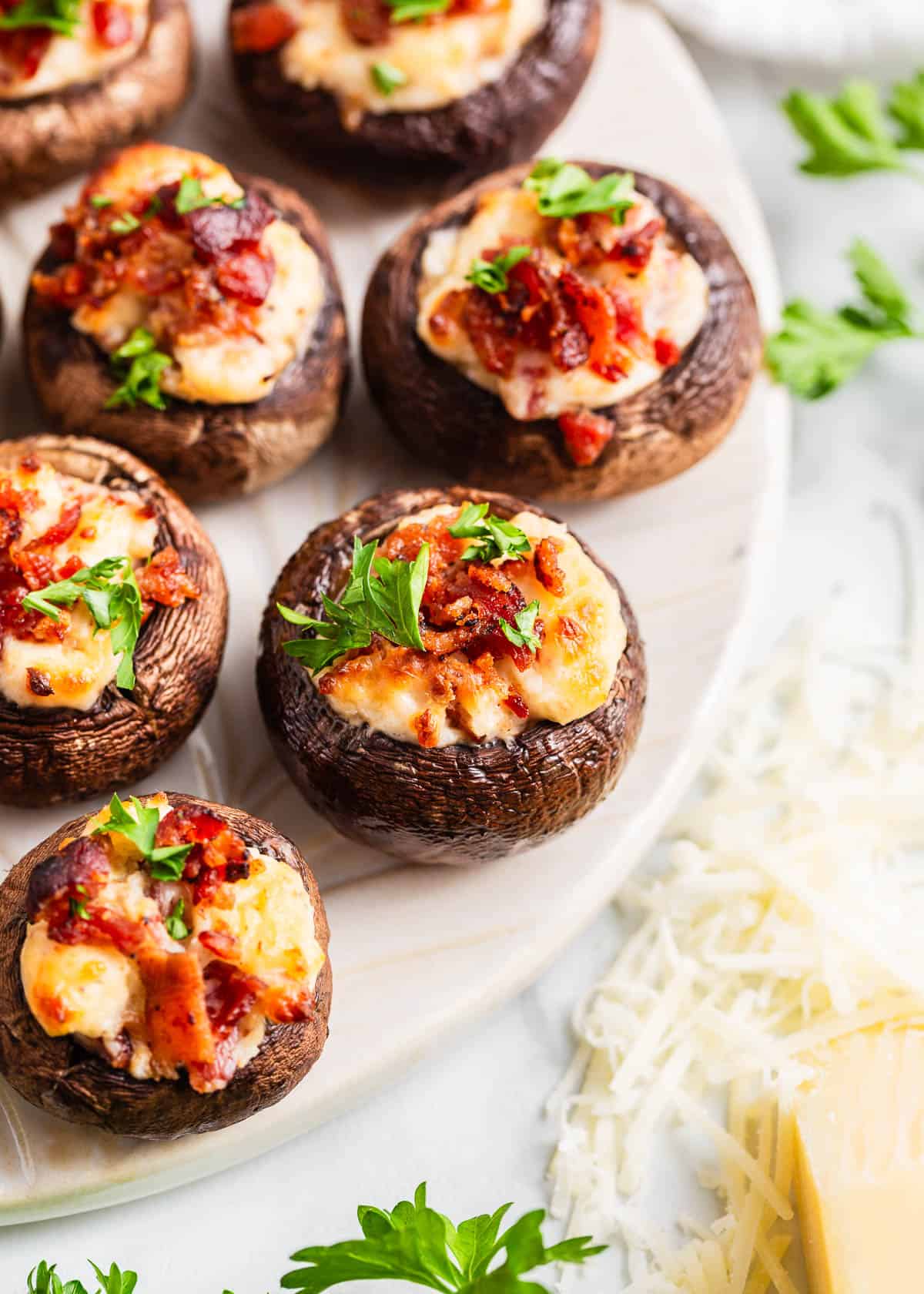 These stuffed mushrooms are made with cremini mushrooms filled with a cream cheese, bacon and Parmesan mixture. These savory bites are the perfect appetizer! Stuffed mushrooms on a plate.