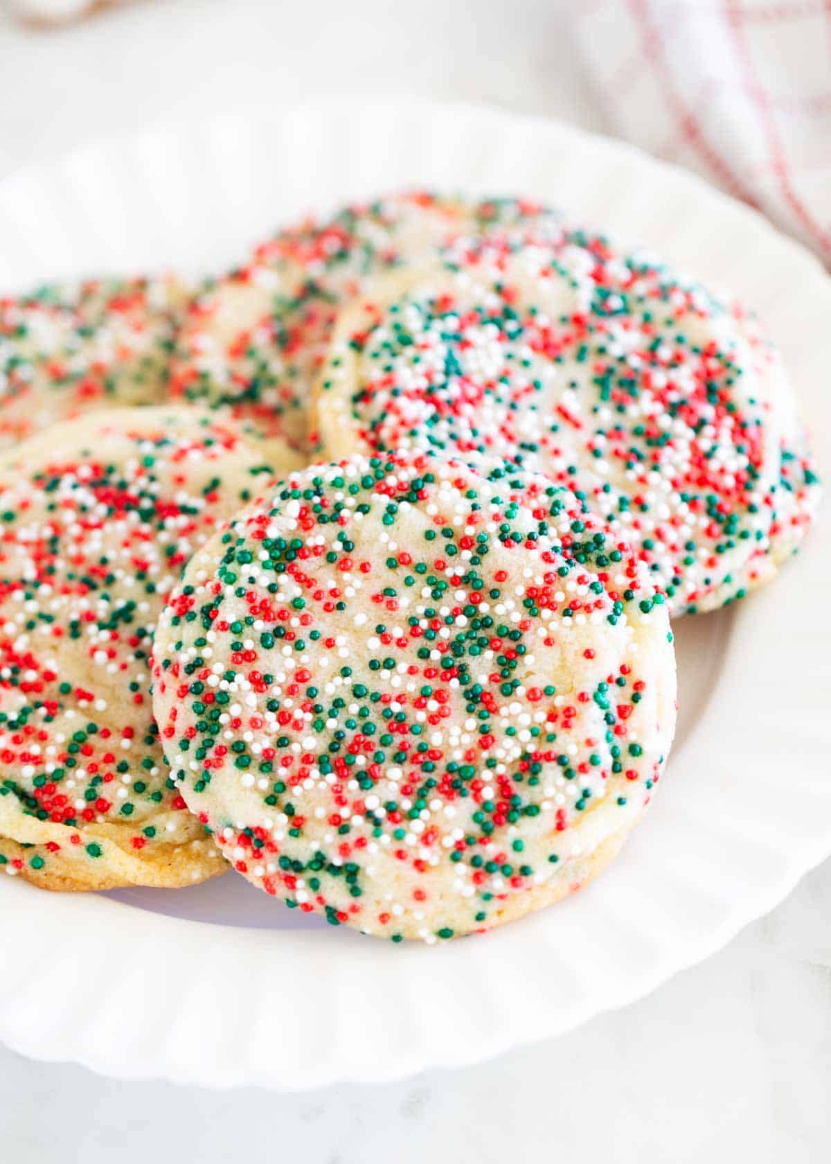 This drop sugar cookies recipe is an easy, no roll sugar cookie that is mixed in one bowl and done in under an hour. They are soft, chewy and buttery with slightly crisp edges. Drop sugar cookies on a white plate.