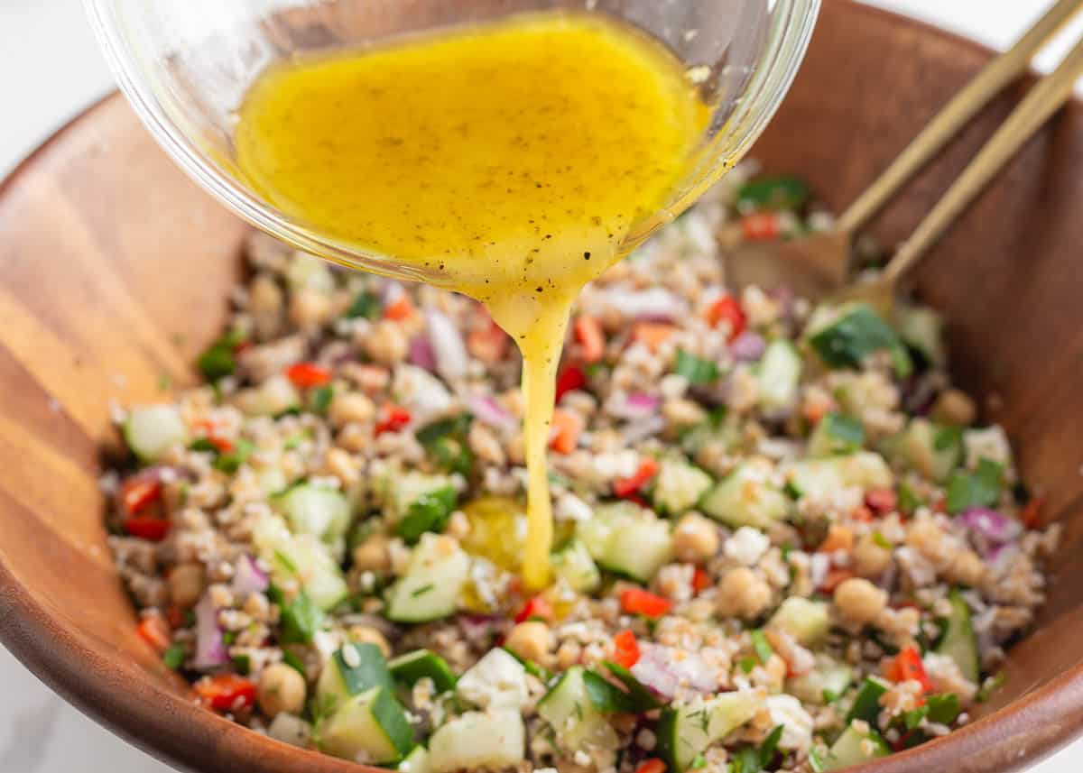 Pouring dressing over the top of salad.