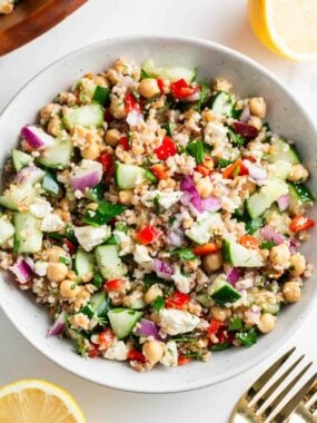 Finished bulgur wheat salad served in a bowl with chickpeas, fresh vegetables, feta cheese, and lemon dressing.