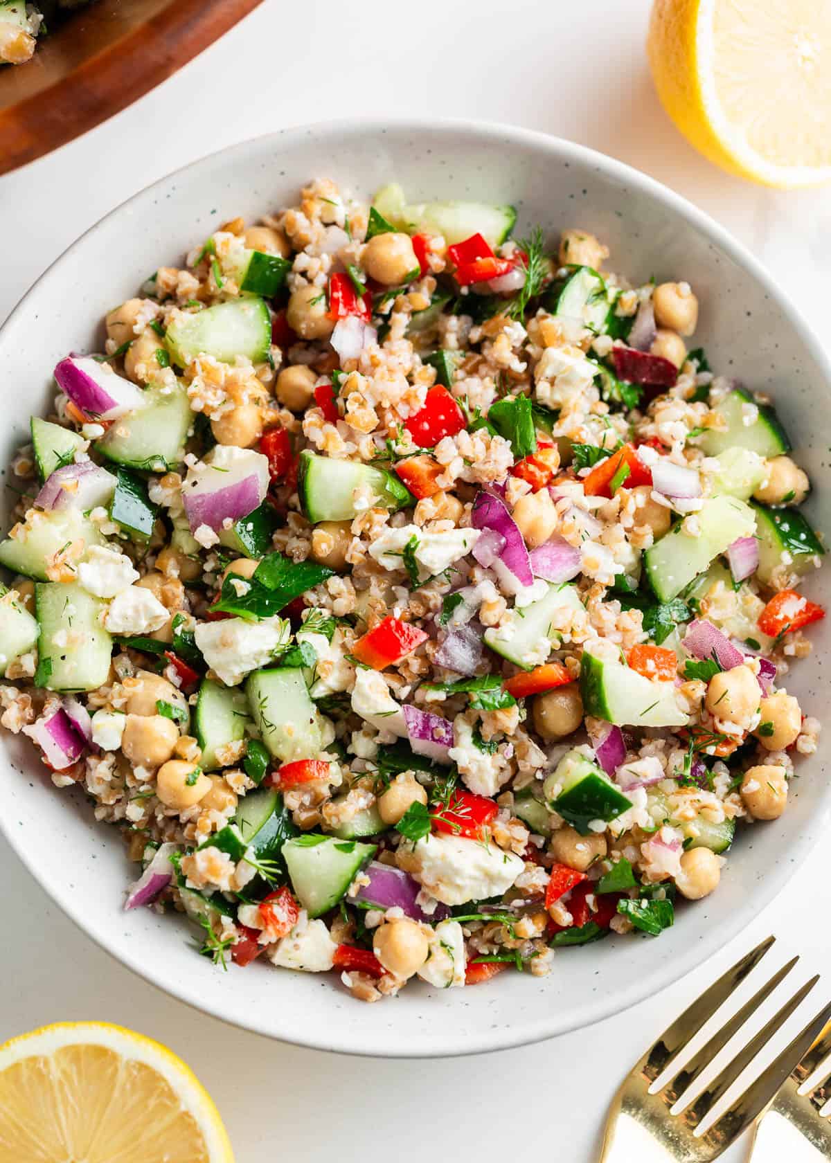 This bulgur salad is easy to make with crisp vegetables, fresh dill, chickpeas, feta cheese and a lemon dressing. Inspired by Middle-Eastern flavors, it's so refreshing and tasty! Bulgur salad in a white bowl.
